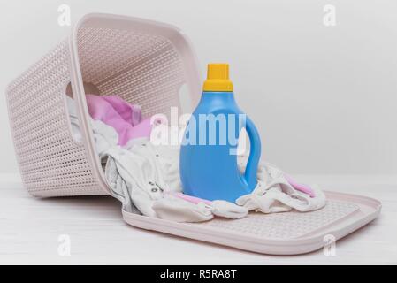 Bottle of laundry detergent in the basket with dirty baby clothes. Stock Photo