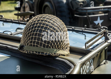 Green military helmet with net on a vehicle Stock Photo