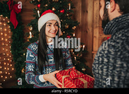 Merry Christmas and Happy New Year . Young couple celebrating holiday at home. Happy young man and woman giving each other gifts. Stock Photo