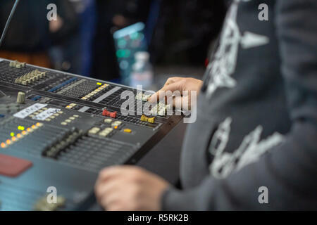 Soundman working on the mixing console. The hand moves one slider. Stock Photo
