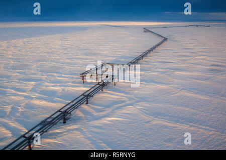 An elevated pipeline running above ground and the frozen tundra from Endicott oil production facility to the Alyaska 1 pipeline in Prudhoe Stock Photo