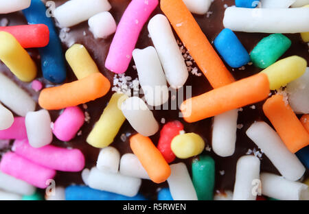 Macro shot of colorful sprinkles on chocolate glazed doughnut for background or banner Stock Photo