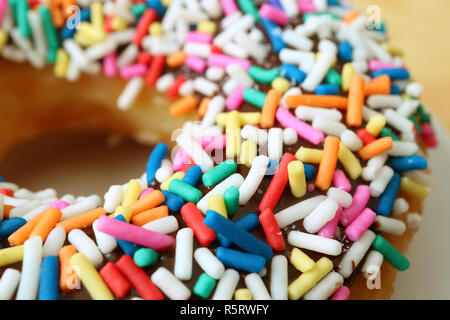 Closed up chocolate glazed doughnut topped with colorful sprinkles Stock Photo