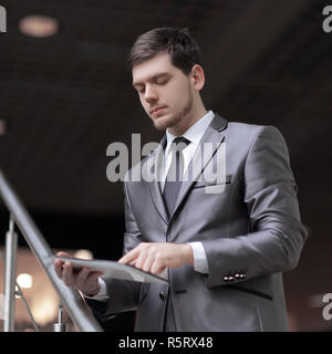 Handsome businessman standing on steps using tablet in office building Stock Photo