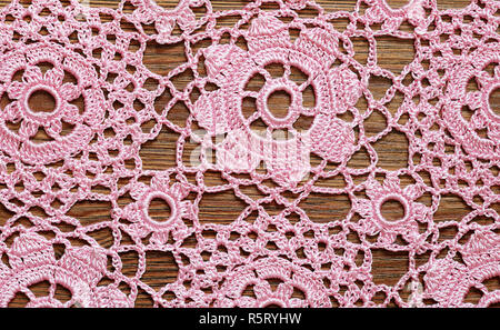 Pink crochet lace on wooden surface Stock Photo