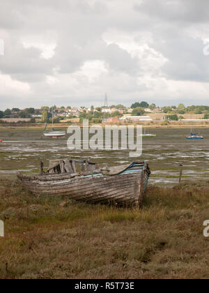 Hull of an old decaying wooden rowing fishing boat with holes in on a ...