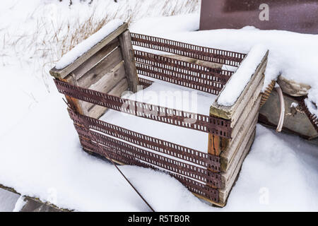 old wooden box with rusty iron sides in the snow Stock Photo