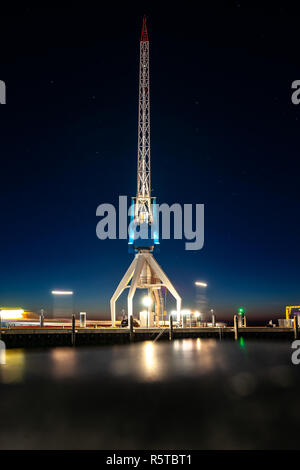 At the dock of the bay a high up crane against a blue starry sky and the red orange colors of the setting sun. Night photography in Harlingen harbor i Stock Photo