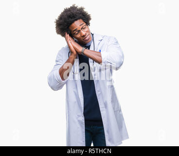 Afro american doctor man over isolated background sleeping tired dreaming and posing with hands together while smiling with closed eyes. Stock Photo