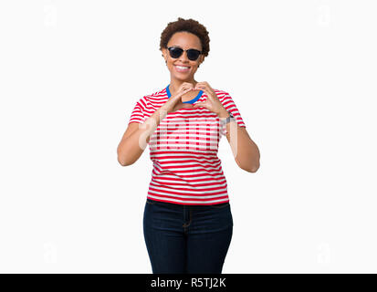 Beautiful young african american woman wearing sunglasses over isolated background smiling in love showing heart symbol and shape with hands. Romantic Stock Photo