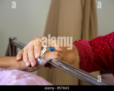 Wife visiting husband in hospital. Senior couple holding hands on hospital bed for hospitalization for supporting his dear. Concept of love and to be  Stock Photo
