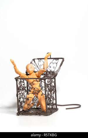 Action figure sitting and hold two hands above the head in open steel cage on isolate background, Concept of tolerance in comfort zone do not dare to  Stock Photo