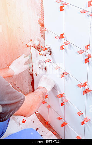 Ceramic tiles. The master lays ceramic tiles on the wall with the help of special devices. . Stock Photo