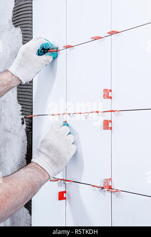 Ceramic tiles. The master lays ceramic tiles on the wall with the help of special devices. . Stock Photo