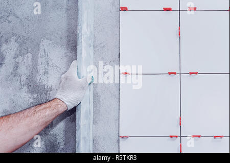 Ceramic tiles. The master lays ceramic tiles on the wall with the help of special devices. . Stock Photo