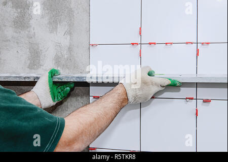 Ceramic tiles. The master lays ceramic tiles on the wall with the help of special devices. . Stock Photo