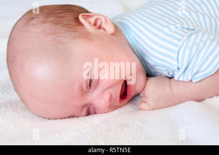 The baby cries and pulls the handle into his mouth because of the cutting teeth. Selective focus Stock Photo