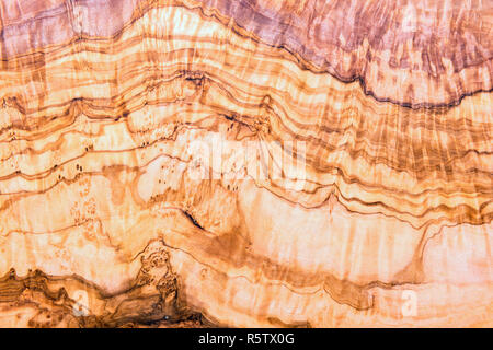 Olive tree plank naturally colored in pink, beige, brown and golden yellow colors. Smooth wooden surface and beautiful folded pattern of annual rings. Stock Photo