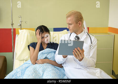 caucasian doctor with suffering patient, using digital tablet Stock Photo
