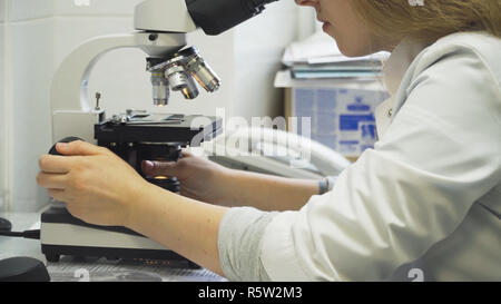 Doctor woman working with a microscope in Laboratory. Female scientist looking through a microscope in lab. Scientist using a microscope in a laboratory. Stock Photo