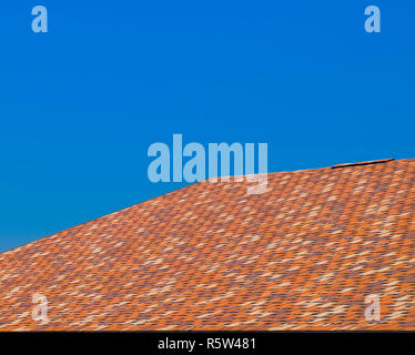 Roof from multi-colored bituminous shingles. Patterned bitumen shingles. Stock Photo