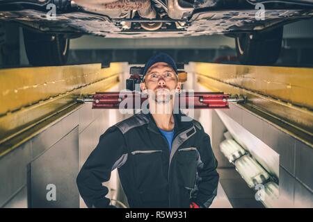 Caucasian Auto Service Worker in His 30s Under the Car Preparing For His Job. Stock Photo
