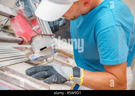 Ceramic Tiles Cutting by Caucasian Construction Worker. Bathroom Remodeling. Stock Photo