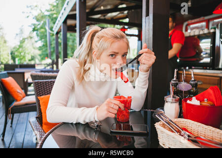 Young beautiful woman eating watermelon in the outdoor restaurant. Funny and beautiful