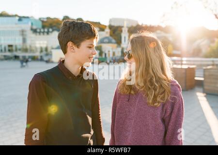 Outdoor portrait of a couple of young boy and girls looking at each other, smiling teenagers in the sunset light, golden hour Stock Photo