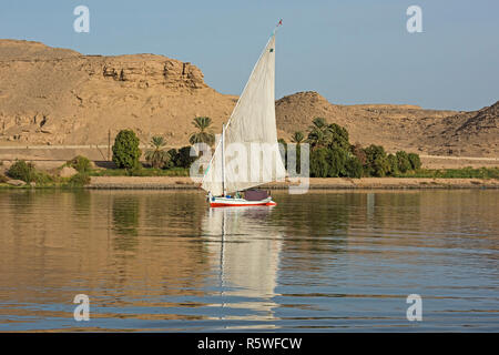 Traditional egyptian felluca sailing boat on river Nile with reflection at Aswan Stock Photo