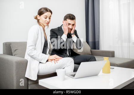 Businessman and woman having a problem sitting together with frustrated emotions on the couch at home or comfortable office Stock Photo