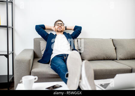 Businessman dressed casually relaxing on the couch while watching TV at home Stock Photo