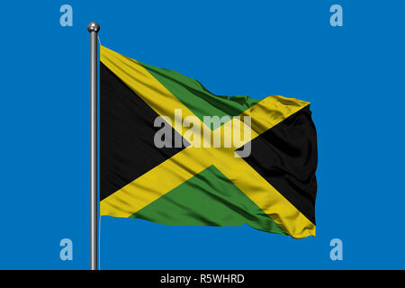 Flag of Jamaica waving in the wind against deep blue sky. Jamaican flag. Stock Photo