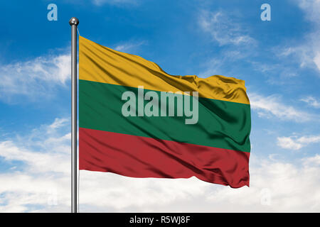 Flag of Lithuania waving in the wind against white cloudy blue sky. Lithuanian flag. Stock Photo