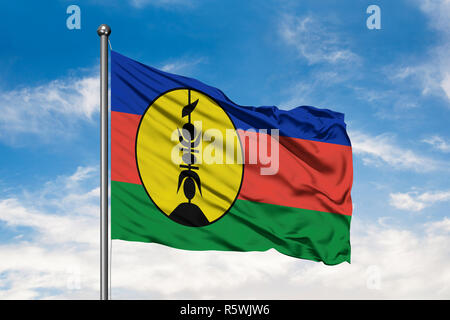 Flag of New Caledonia waving in the wind against white cloudy blue sky. Stock Photo