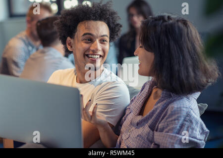startup business and new mobile technology concept with young multiethnic couple in modern bright office interior working on laptop and tablet computer on new creative project and brainstorming Stock Photo