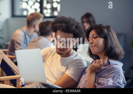 startup business and new mobile technology concept with young multiethnic couple in modern bright office interior working on laptop and tablet computer on new creative project and brainstorming Stock Photo