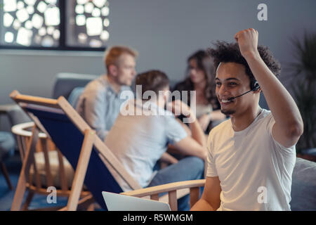 Laughing african american hipster software developer at computer at office of startup company Stock Photo
