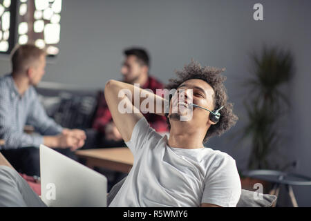 Laughing african american hipster software developer at computer at office of startup company Stock Photo