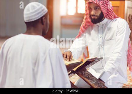Muslim men praying with holy books in mosque Stock Photo