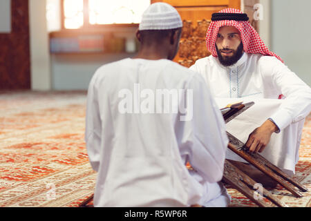 Muslim men praying with holy books in mosque Stock Photo
