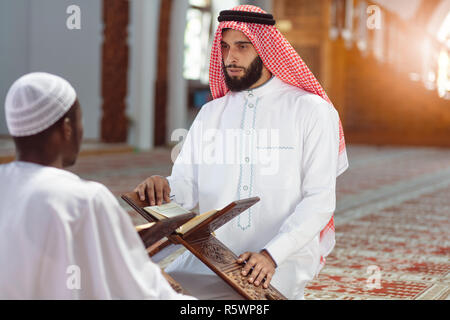 Muslim men praying with holy books in mosque Stock Photo