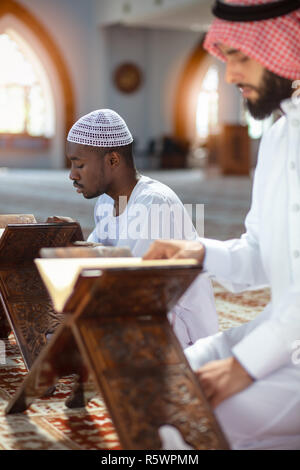 Muslim men praying with holy books in mosque Stock Photo