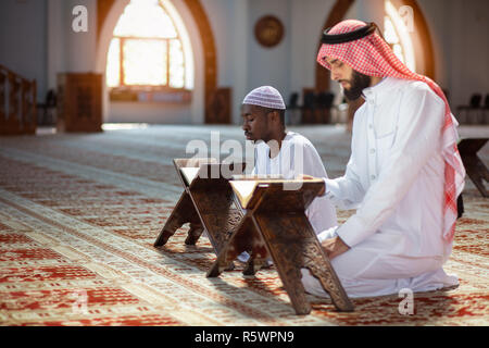 Muslim men praying with holy books in mosque Stock Photo