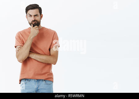 Smart intelligent thoughtful good-looking male squinting suspiciously while thinking rubbing beard making decision listening carefully to wife trying  Stock Photo