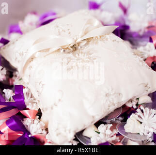 Wedding ring on a decorative cushion with purple decorative ribbons. Stock Photo