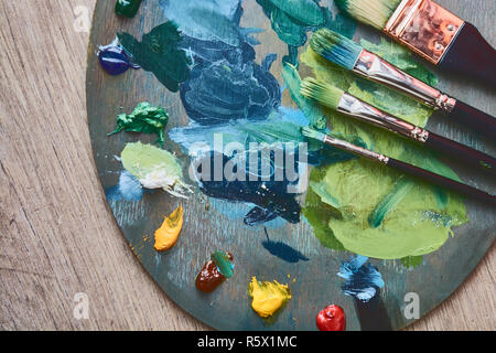 Artist palette with oil paints and brushes on a wooden background. Hobby painting concept. Stock Photo