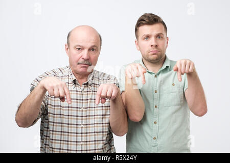 Two mature men being sad and pointing down. Stock Photo