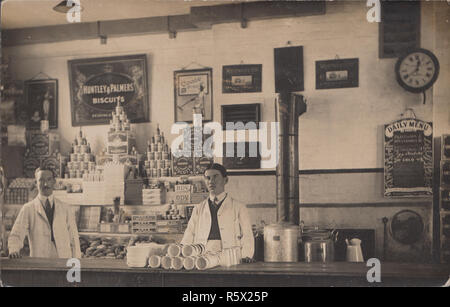 Vintage Photographic Postcard Showing Staff Inside an Edwardian Store or Restaurant / Café. Signs For Huntley & Palmers Biscuits and Peak Frean Digestive Biscuits. Two Pictures of Westward Ho on The Back Wall Stock Photo