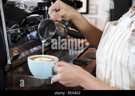Close-up hand of barista making latte or cappucino coffee in coffee shop. Cafe restaurant service, food and drink industry concept. Stock Photo